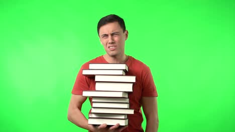 man struggling to carry a large stack of books on green screen