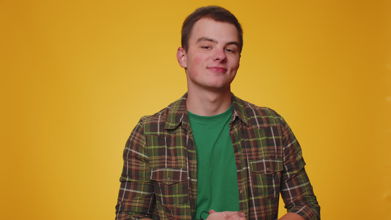 Um jovem alegre de camisa a olhar para a câmara a fazer um gesto de telefone a dizer: "Ei, liga-me de volta".