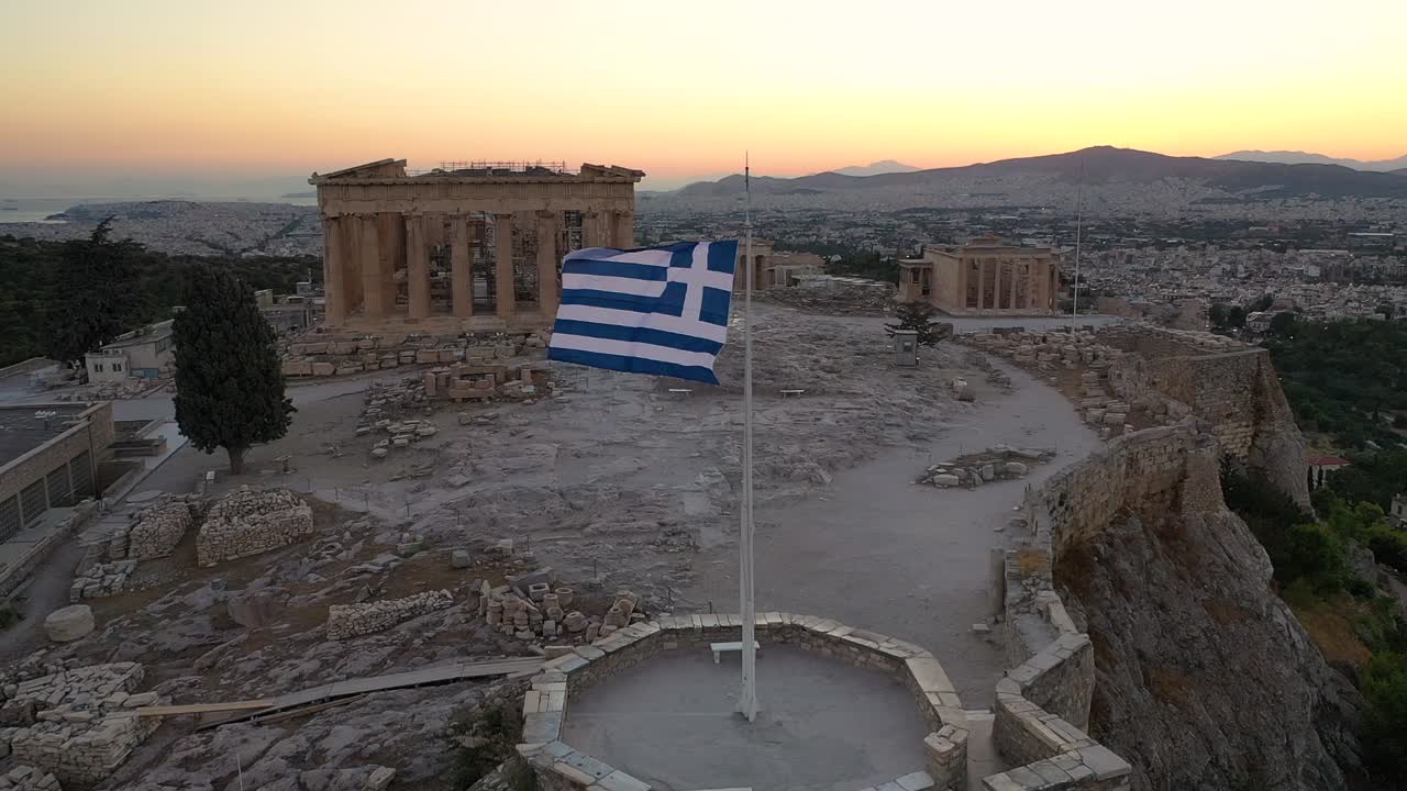 toma cinematográfica de la bandera de grecia, acrópolis ciudad de atenas partenón, monte lycabettus, edificio del parlamento y edificios residenciales, puesta de sol en atenas, grecia