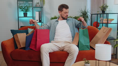 hombre adulto feliz adicto a las compras consumidor regresó a casa después de la venta de compras en línea con bolsas en casa