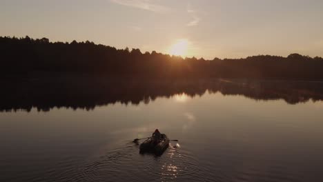 person in a rubber boat at the lake with reflection of a vibrant sunset in rogowko, poland