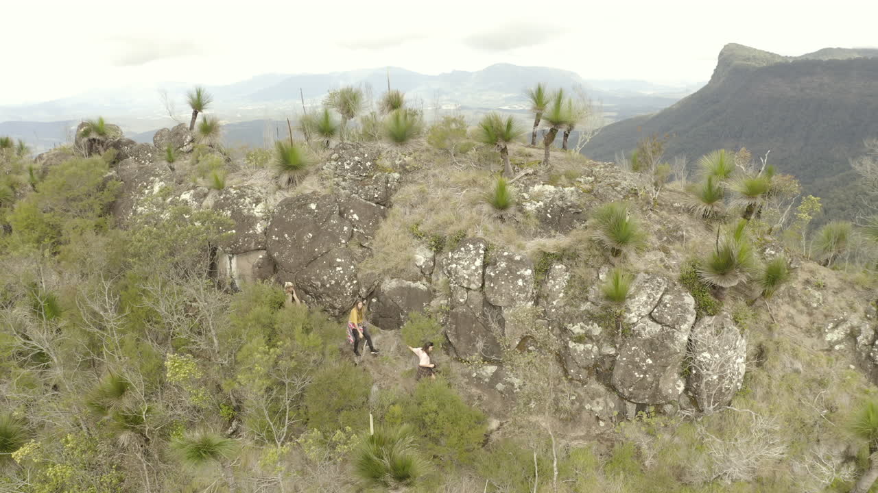 toma de dron de 4k de excursionistas caminando al lado de un acantilado de montaña en el parque nacional border ranges, nueva gales del sur, australia