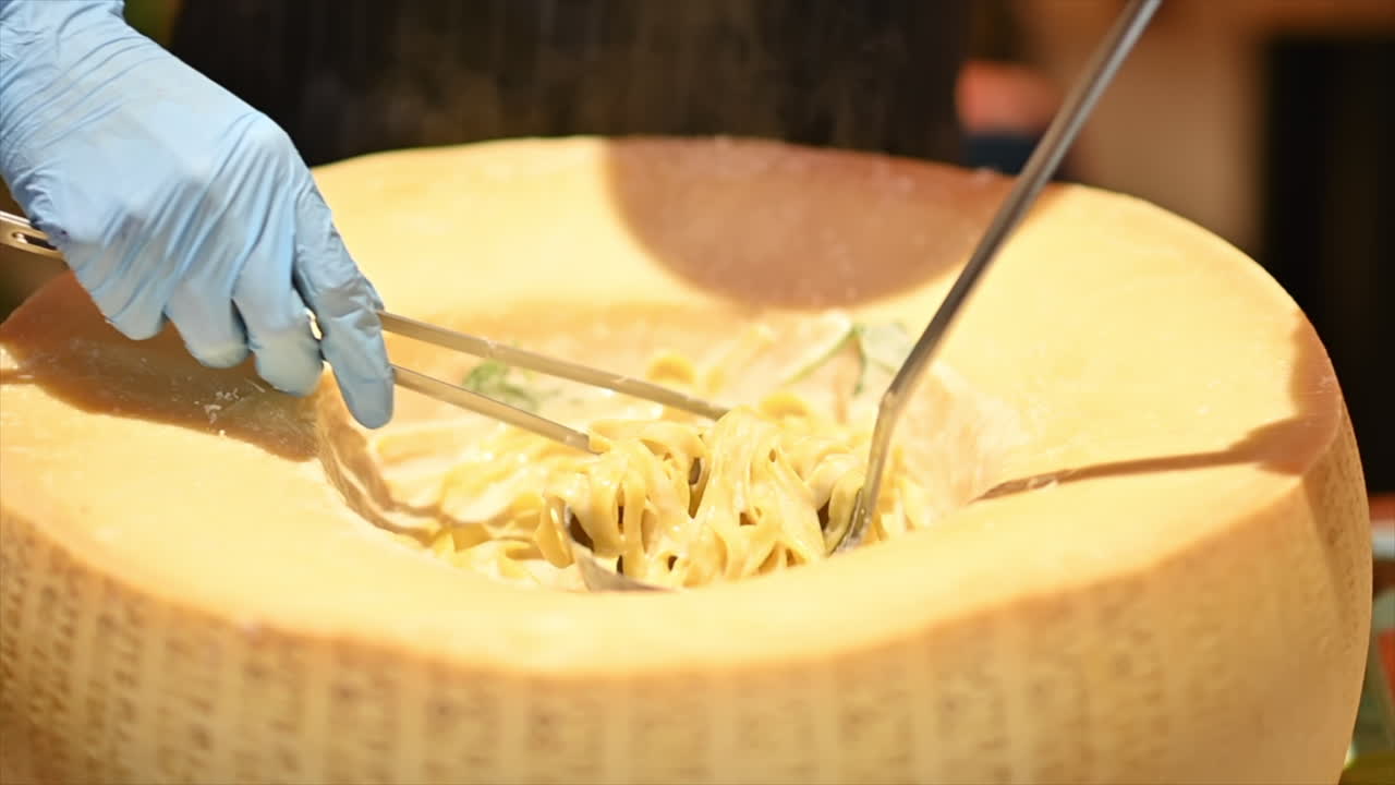 Chef preparing pasta in a big parmesan wheel, slow motion