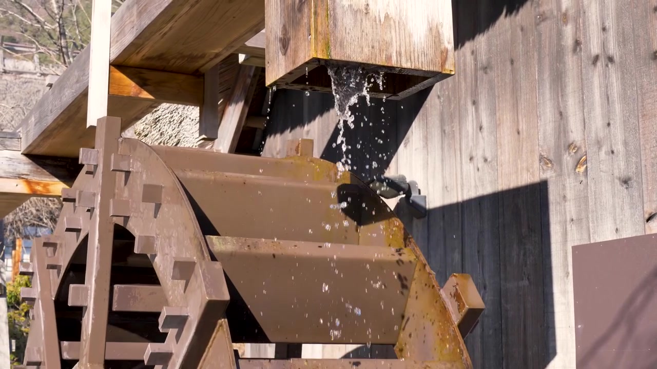 Slow motion close-up of a traditional wooden water wheel mechanism spinning to generate energy in a small Japanese town village near Lake Saiko Minamitsuru District Asia industry and tourism