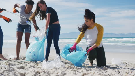 diverse group of female friends putting rubbish in refuse sacks at the beach