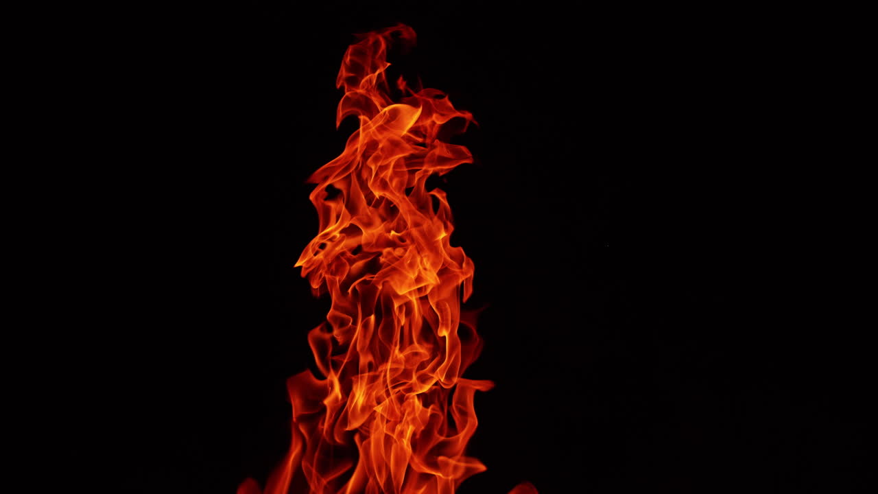 Long flame of bonfire rising into the air. Hot fire isolated on the black background.