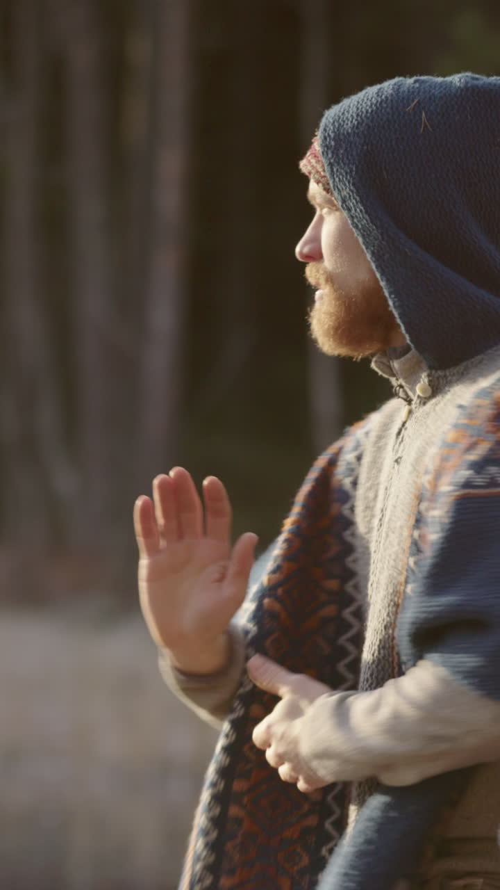 A handsome bearded viking man warming up doing qigong tai chi, vertical
