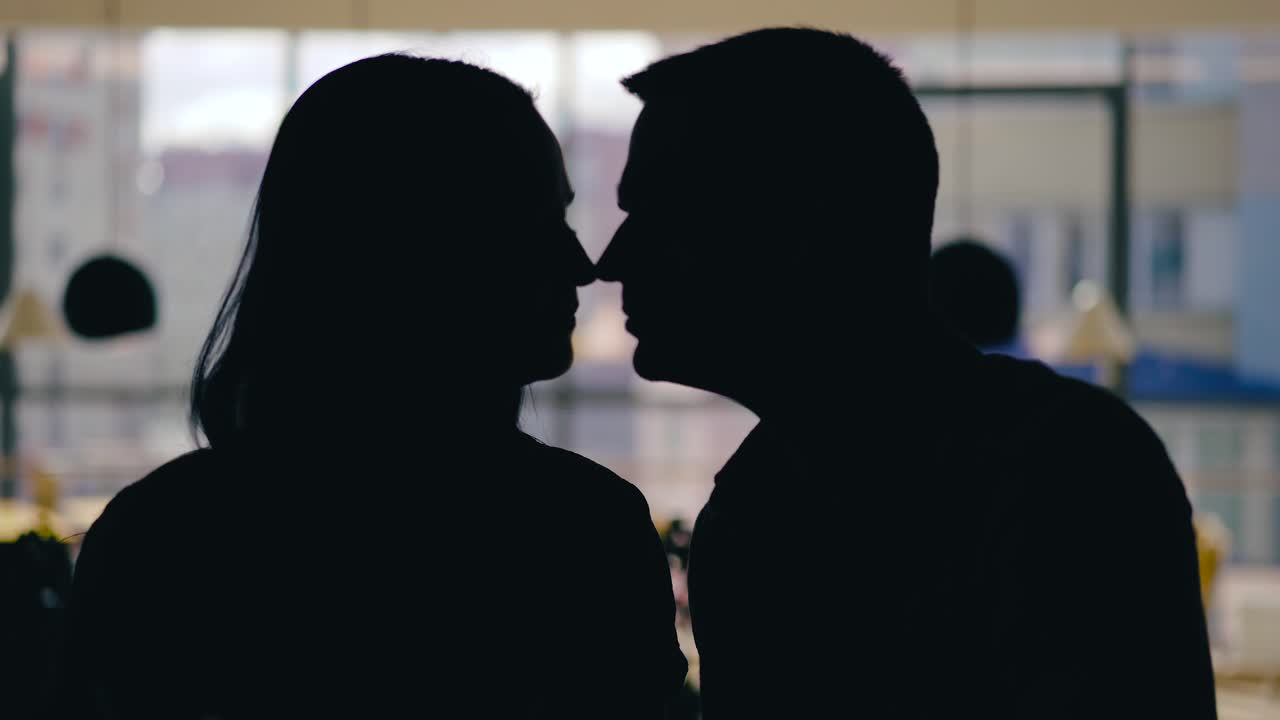 romantic couple are kissing in the cafe at table in the day. Motion of silhouettes
