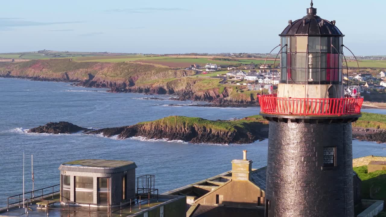 Ballycotton lighthouse overlooks rocky coastline in Cork, Ireland, on a sunny day