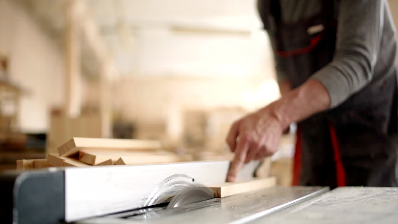 manos de un carpintero irreconocible usando una sierra circular para cortar una tabla de madera
