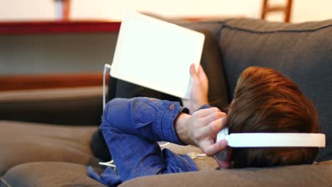 hombre escuchando música en una tableta digital en la sala de estar