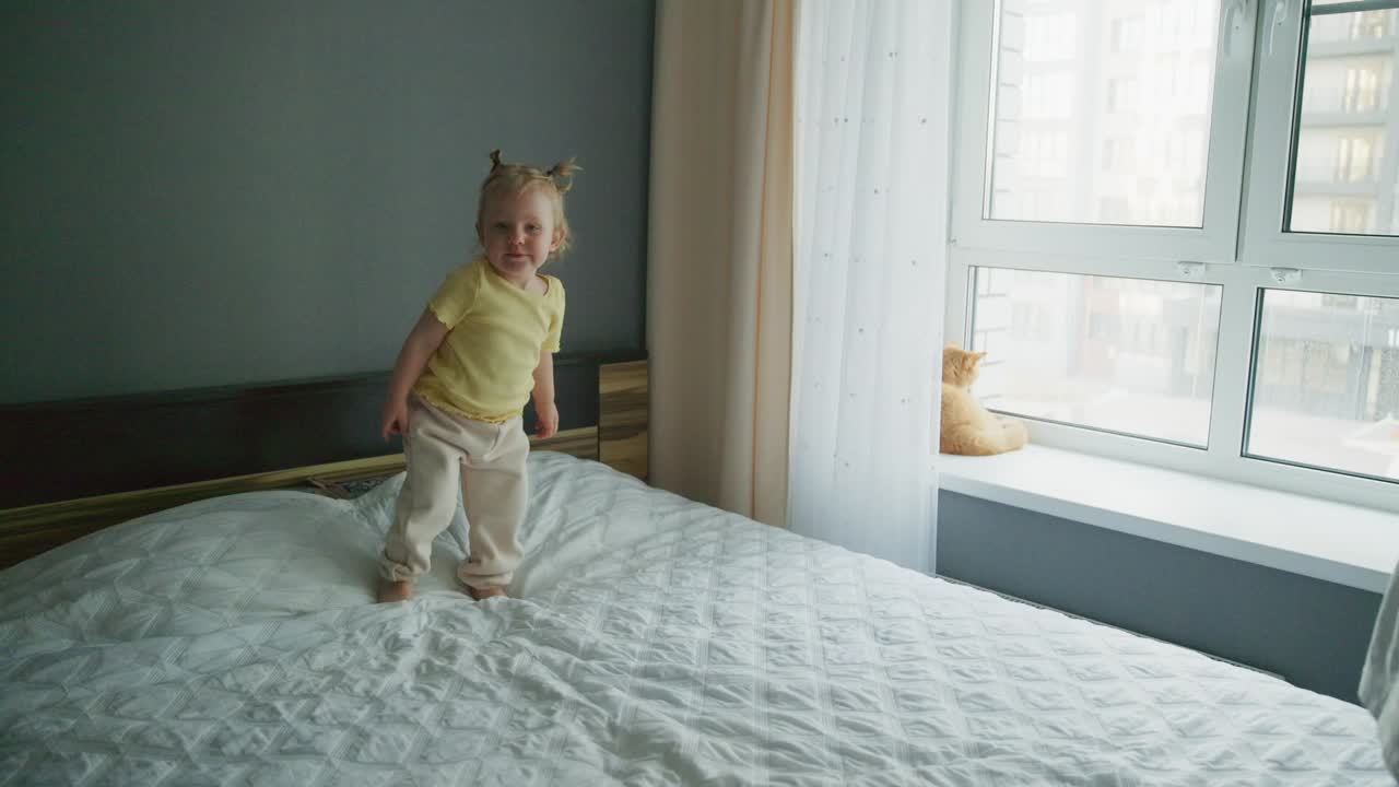 Criança feliz aprendendo a andar na cama com a mãe.