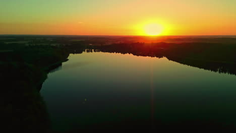 The-awesome-aerial-view-of-a-radiant-golden-sun-lighting-up-the-sky-with-an-eye-catching-lake-encircled-by-lush-greenery-adds-a-flawlessly-captured-horizon-to-the-mix