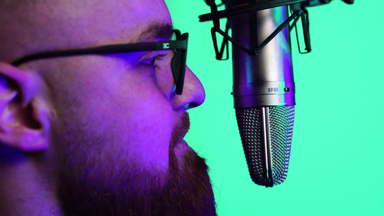 Man With Beard and Glasses Speaking in Front of Professional Microphone With Green Screen Background