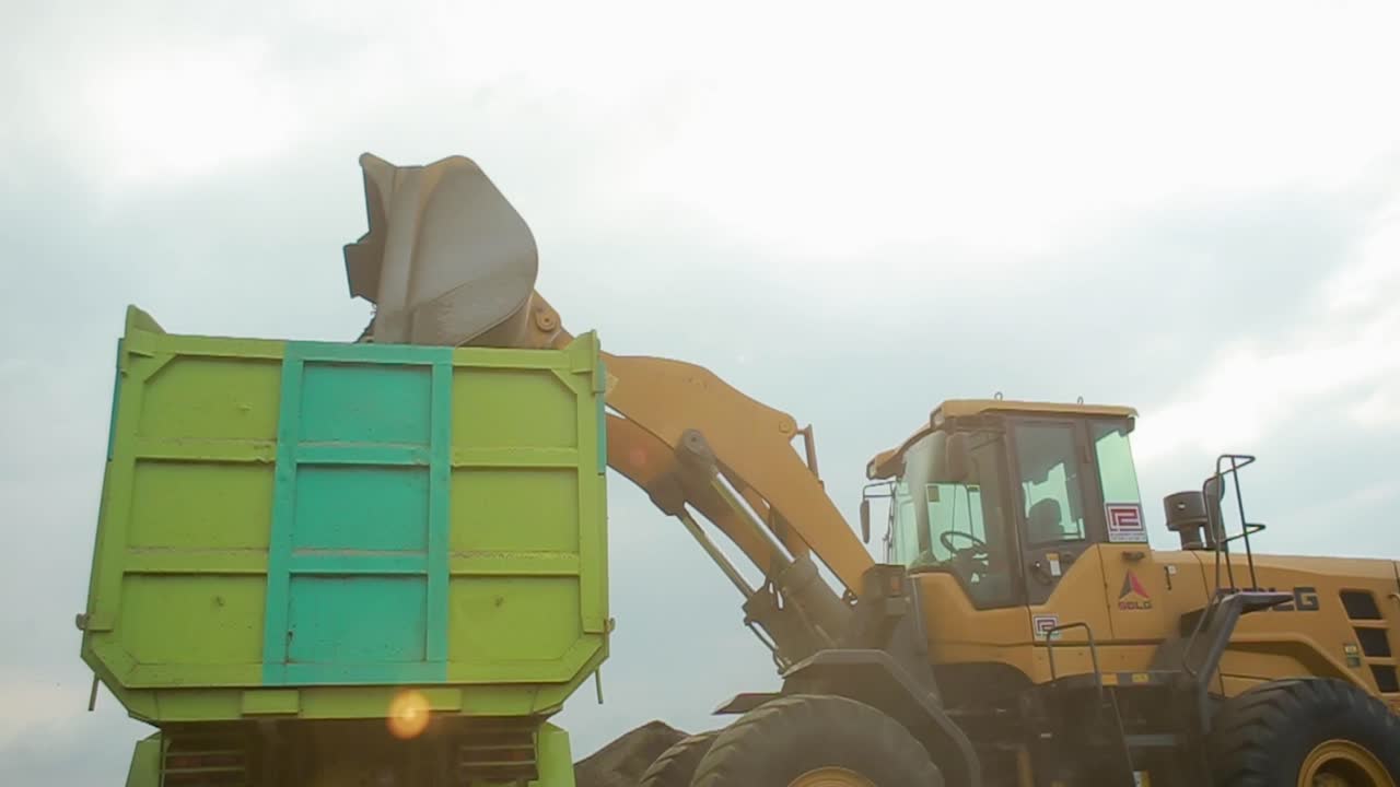 West Java Indonesia - February 11, 2002 : Heavy construction machinery excavator in open pit mining - wheel loader transporting sand to truck or trailer in asphalt plant.