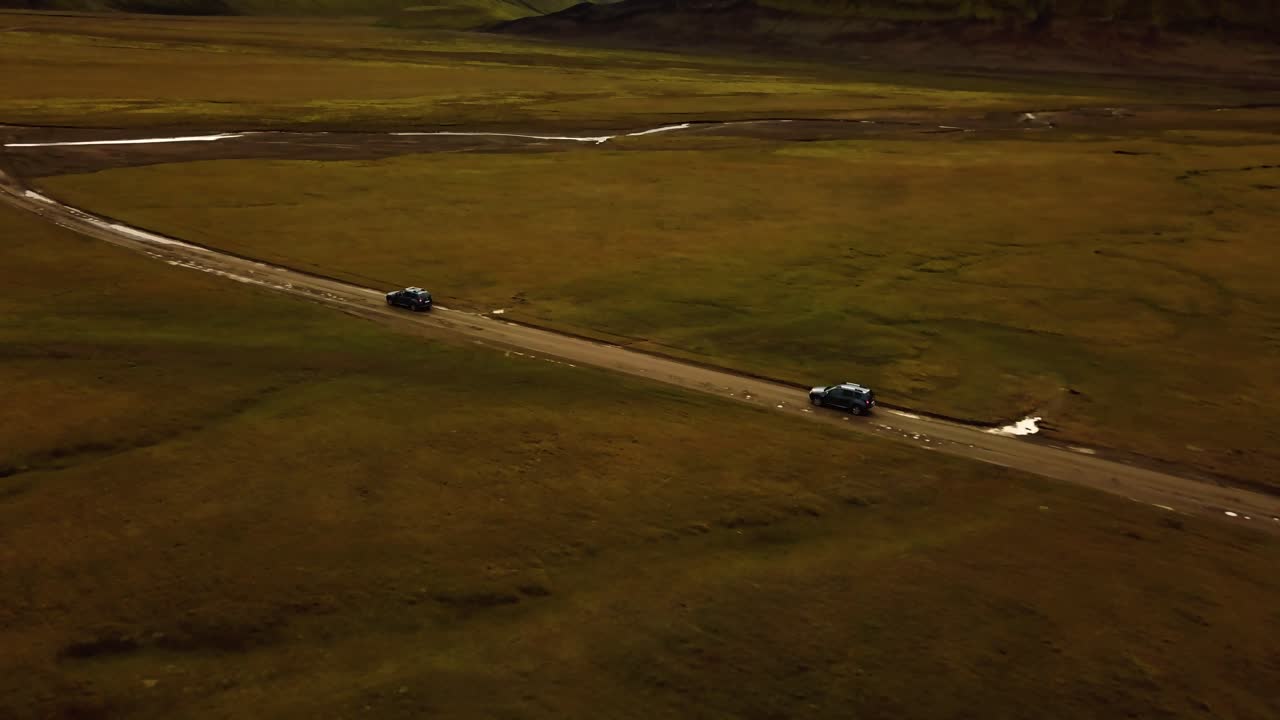 아이슬란드 고원을 통과하는 비포장 도로에서 과속하는 두 대의 자동차에 대한 공중 전망
