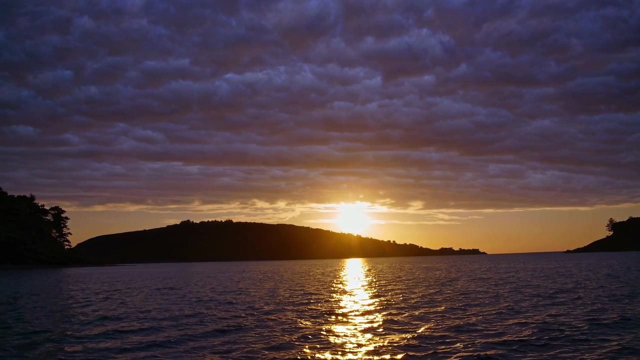 Golden Sunset Over Calm Ocean Waters With Silhouetted Island