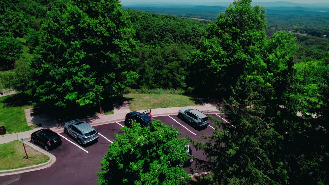 Lush Green Trees and Blue Sky with Distant Hills and Parking Lot