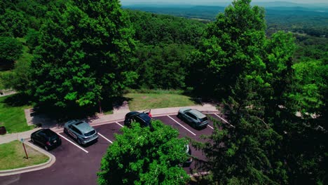 lush green trees and blue sky with distant hills and parking lot