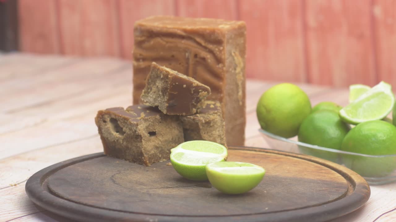 Close-up hands cut lemon together amber-colored block made from cooked and dried sugarcane juice is used to Venezuelan desserts and Papelón con Limón drink