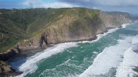 Acantilados-Rocosos-Junto-Al-Mar-De-La-Playa-De-Arena-Negra-De-Piha-En-La-Isla-Norte,-Auckland,-Nueva-Zelanda