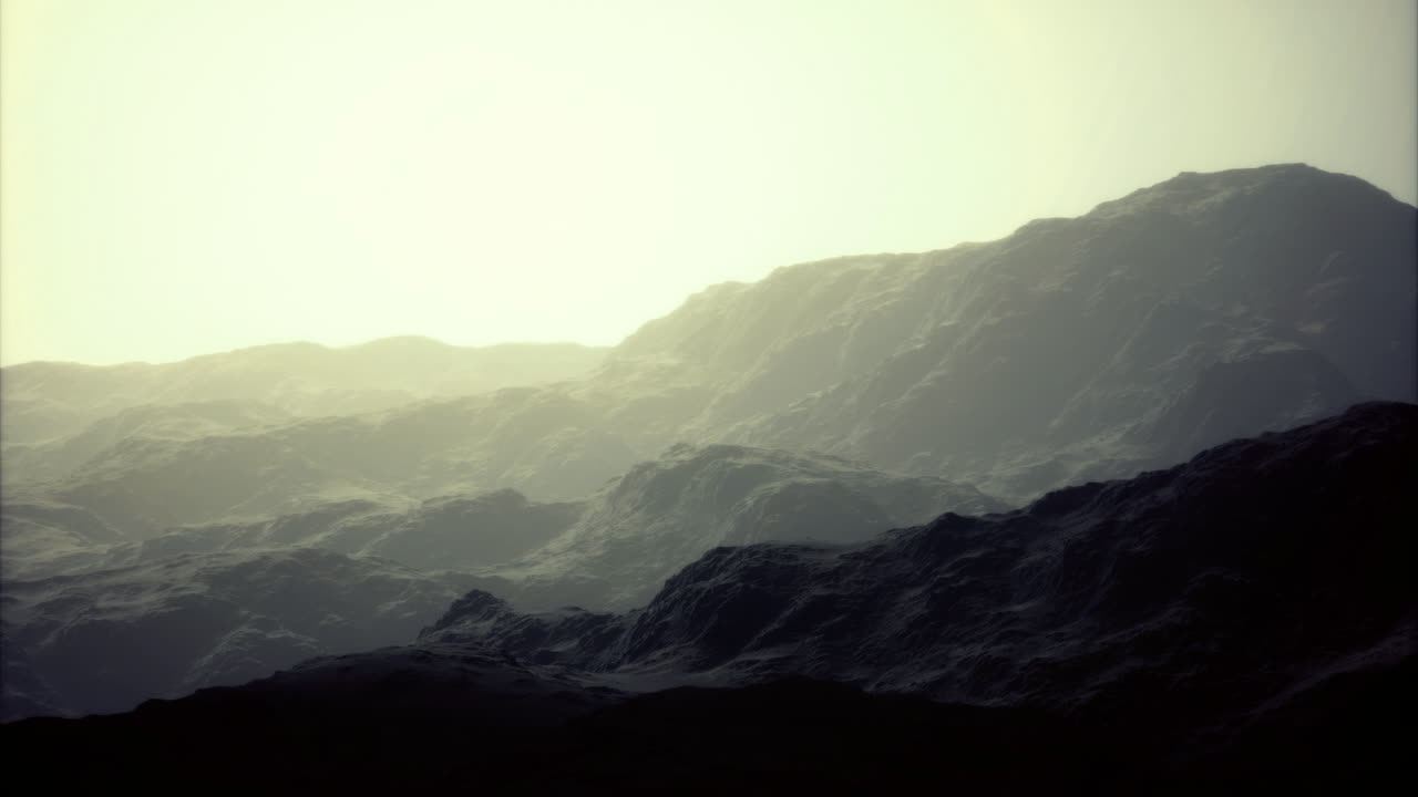 Shadows dance in soft light over rugged mountains at dawn