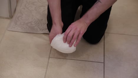 man rolling up a used diaper on bathroom floor