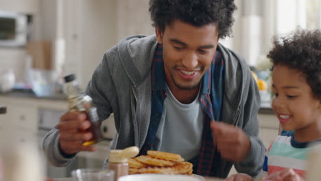 happy-little-boy-eating-fresh-waffles-with-family-for-breakfast-father-pouring-honey-preparing-delicious-homemade-treat-for-son-in-kitchen-at-home-4k