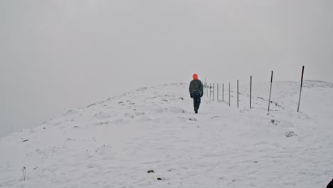 Senderismo-En-La-Nieve-De-La-Montaña,-Vista-Trasera-Del-Hombre-Camina-En-El-Pico-De-La-Montaña-Durante-La-Nevada