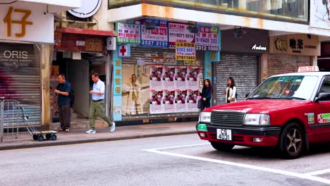 red taxi passing by pedestrians in hong kong