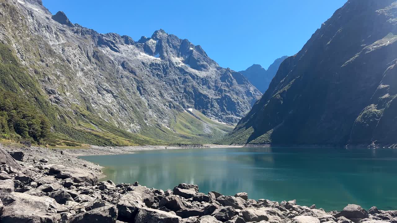 Der Lake Marian, ein atemberaubend blauer See im Fiordland National Park in Neuseeland, ist von hoch aufragenden Bergen umgeben. Kristallklares Wasser und malerische Landschaften schaffen eine friedliche alpine Aussicht.