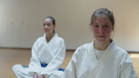 front view of cheerful martial artist sitting on floor in gym