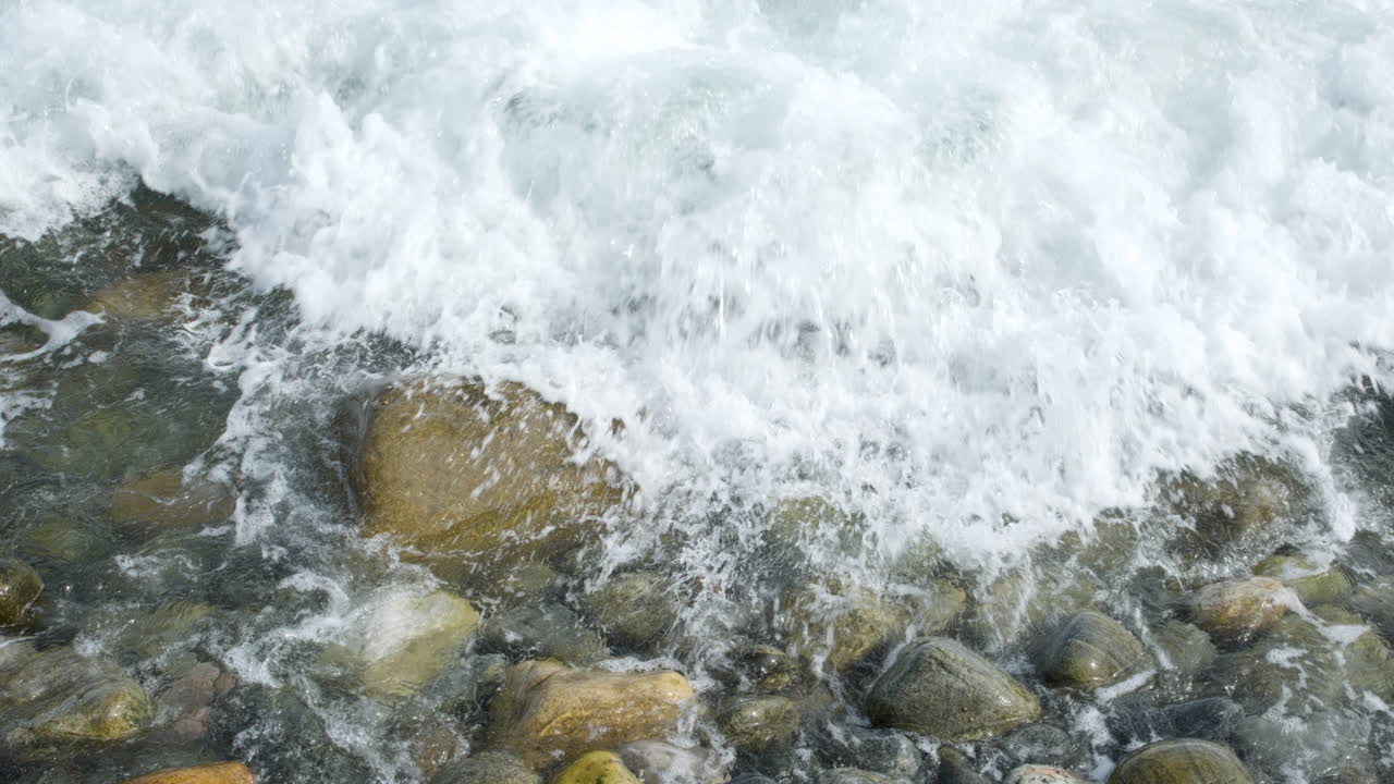 Onde del mare su ciottoli e pietre grandi - primo piano.