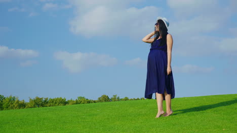 Una-Mujer-Elegante-Con-Un-Sombrero-Y-Gafas-De-Sol-Esperando-Un-Niño