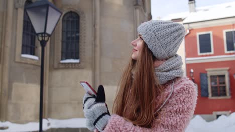 Young-traveler-woman-walking-along-old-city-holding-mobile-phone,-chatting-with-friends-and-family