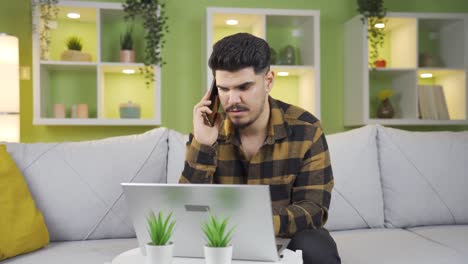 Teenager-working-on-laptop-at-home-getting-angry-on-phone-call.