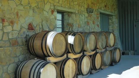 barriles de vino apilados contra la pared de roca áspera en la granja