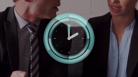 Animation-of-neon-ticking-clock-over-caucasian-businessman-and-businesswoman-discussing-at-office