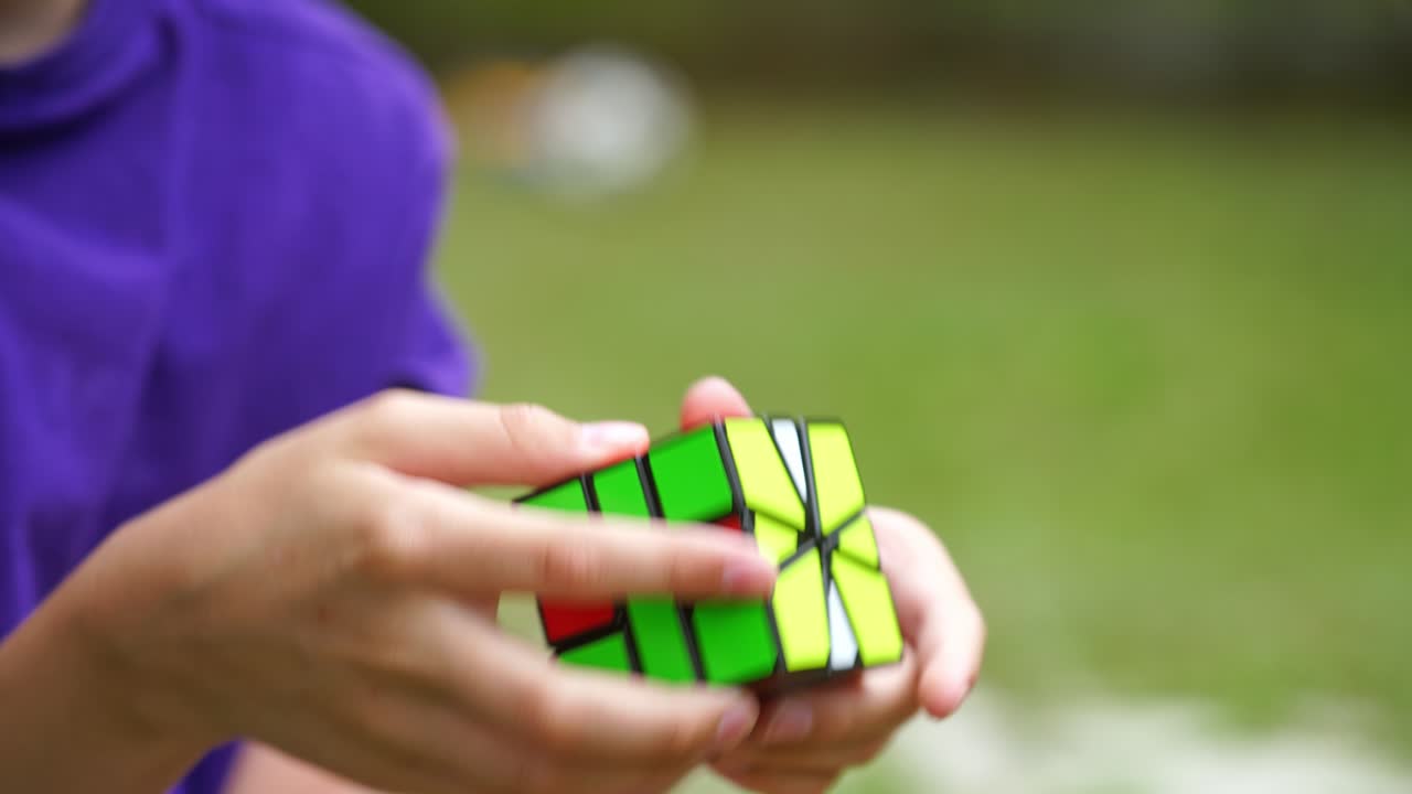Boy is playing with popular rubik's cube outdoors. Smart kid develops his logic with square intelligent toy of colorful cube. Solution, focus and goal concept.
