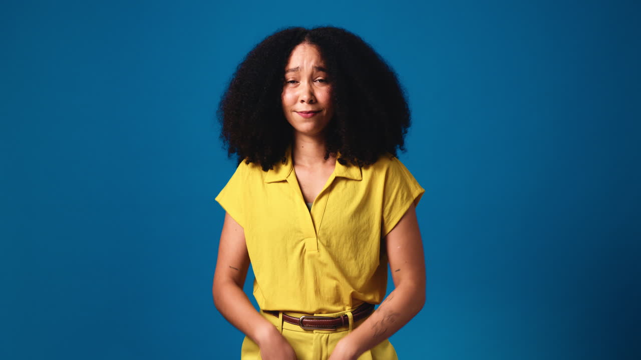 Woman with Curly Hair Shrugging in Yellow Outfit