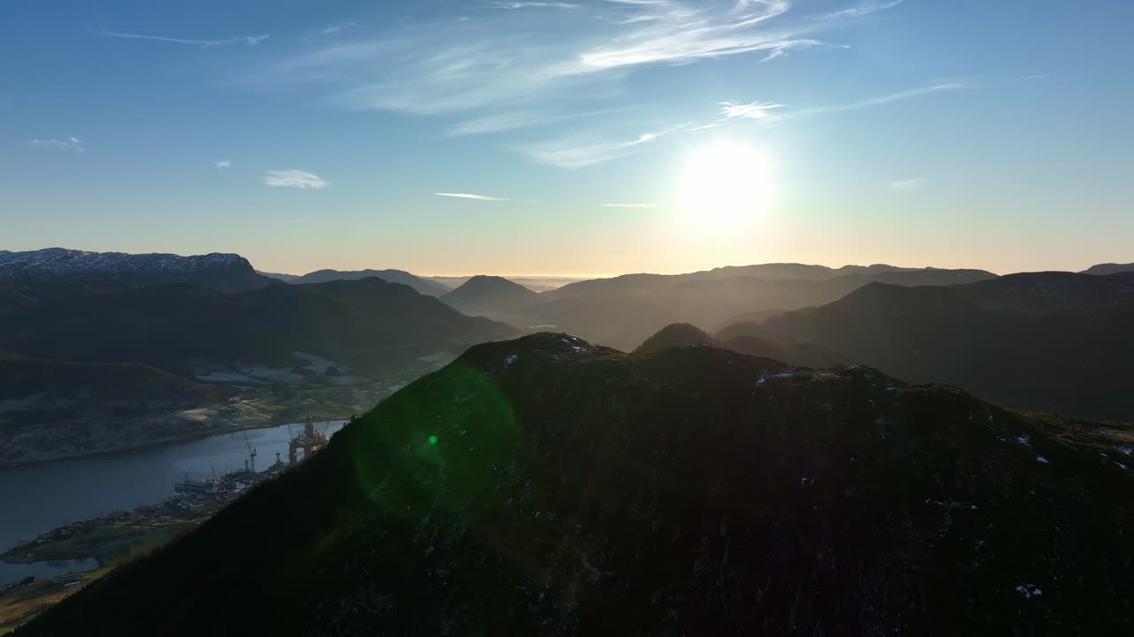 Rising aerial with sun flares and haze reveals Olen from Katanuten peak in sunset. Spring in Vindafjord