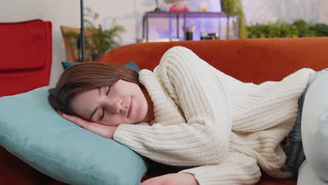 tired young woman girl lying down in bed taking a rest at home, napping, falling asleep on sofa