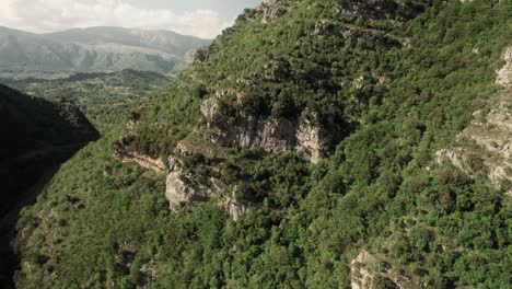 Aerial-circle-view-of-rock-face-with-the-backdrop-of-a-beautiful-valley