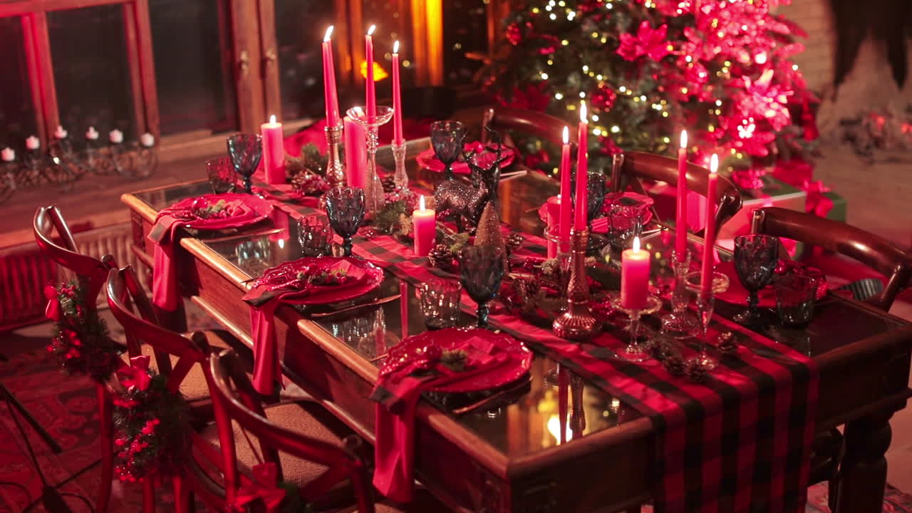 Bright festively decorated table for six people. Lighted candles in the beautiful room with Christmas tree in the corner.