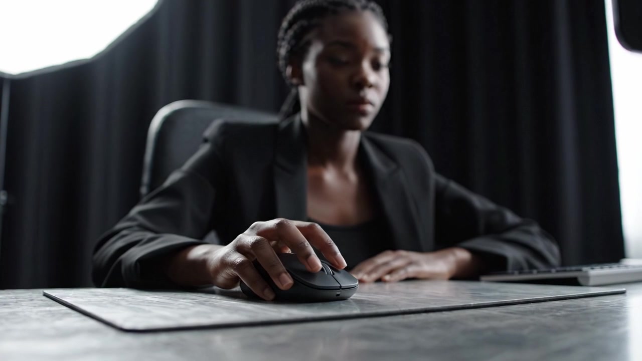 Focused Business Professional Working at Desk with Mouse and Laptop in Modern Office Environment, Portraying Concentration and Productivity