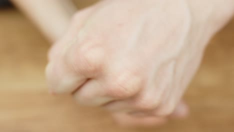 Fingers press together as part of a sleight of hand illusion to make a ring vanish. Captures dexterity, mystery, and subtle magic movement in a close-up indoor setting