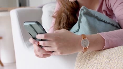 mujer caucásica feliz hablando en un teléfono inteligente en una sala de estar soleada, cámara lenta