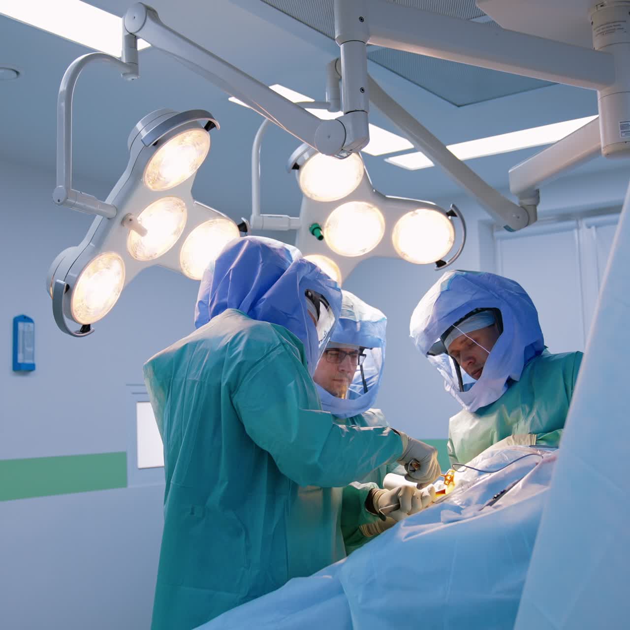 Professional doctors perform arthroscopic operation on patient's knee. X-ray shot of injured leg on the wall