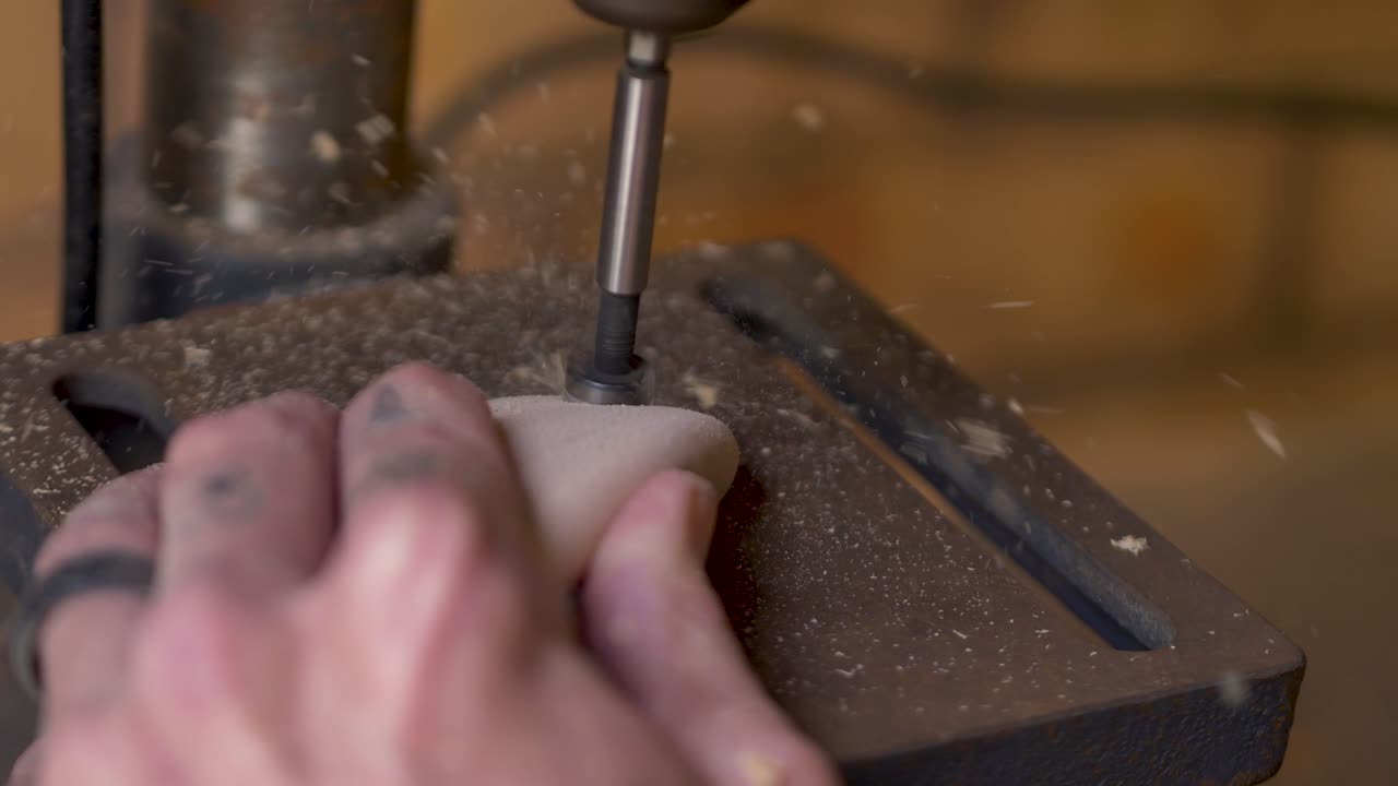 Slow motion close-up of man's fingers holding wooden indoor climbing block holds and drilling hole with dust wooden particles coming from tool machinery at home woodwork garage shed Australia industry