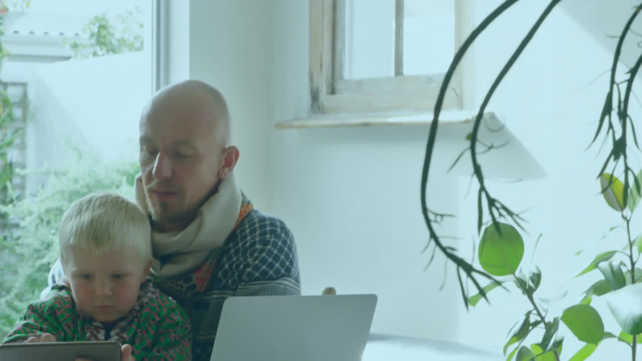 анимация слов оставаться дома над белым мужчиной с ребенком с помощью его ноутбука